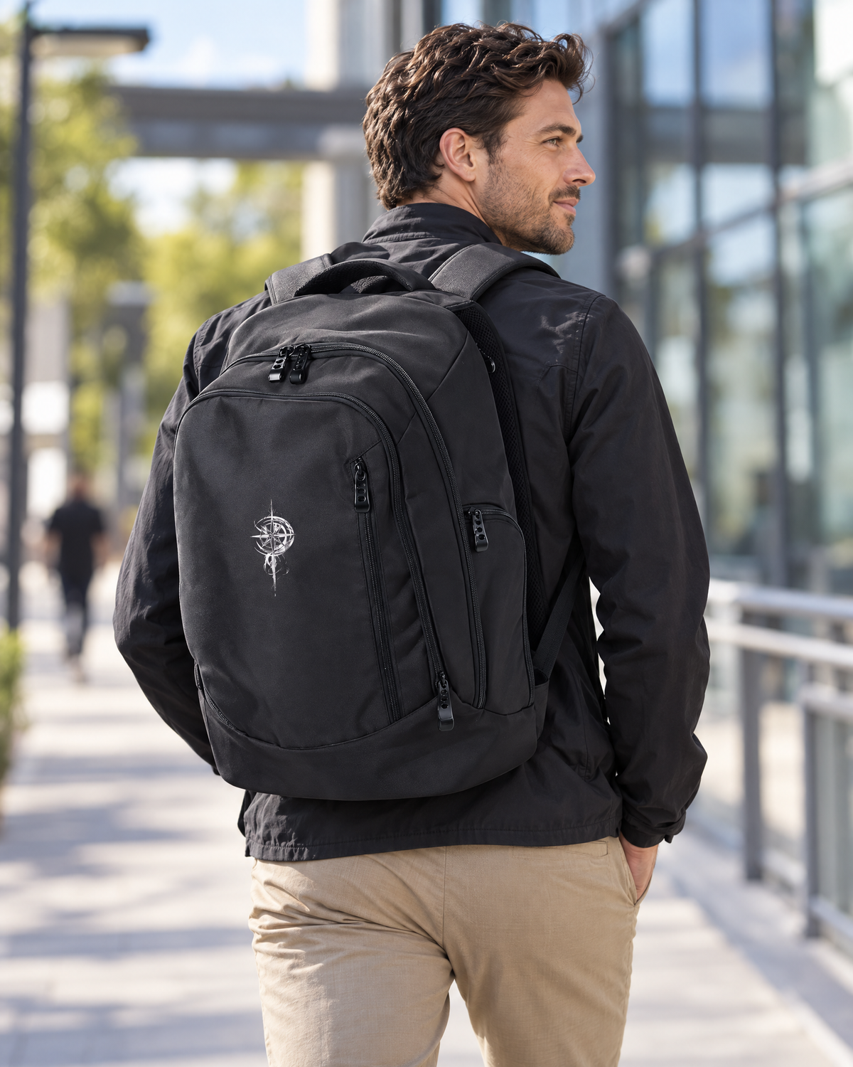 Man wearing black Grit With Faith tech backpack with embroidered compass in an urban setting