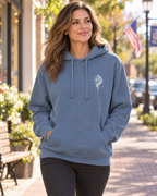 Woman wearing Blue Jean Grit With Faith garment-dyed hoodie with embroidered compass outdoors